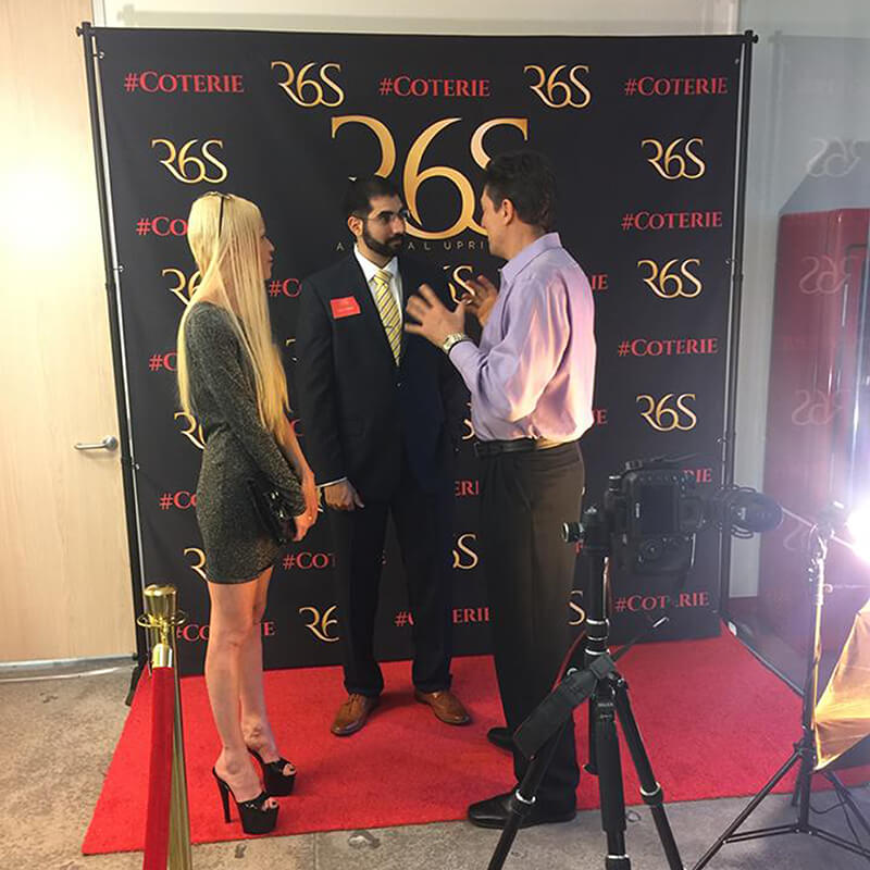 A custom 8 by 8 foot step and repeat with red carpet and stanchions for R6S
