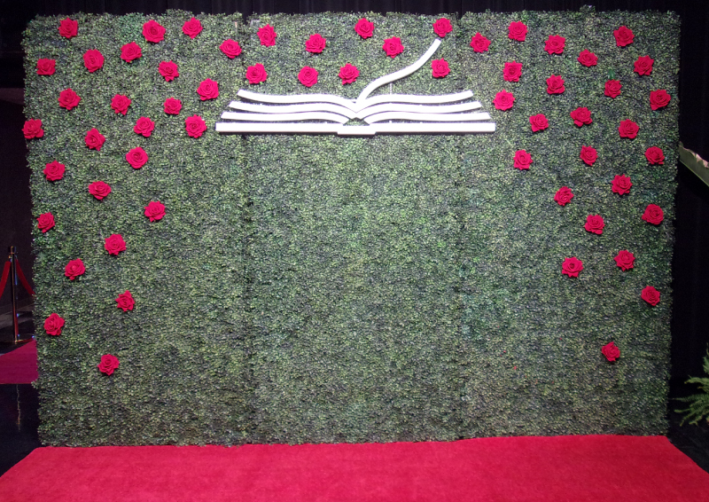 Hedge walls with flowers and cut-out logo.